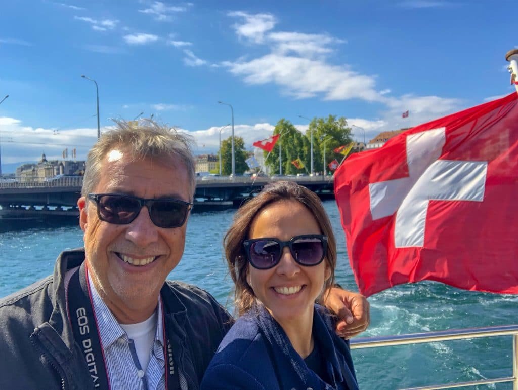 Homem e mulher abraçados dentro de barco perto de bandeira da Suíça