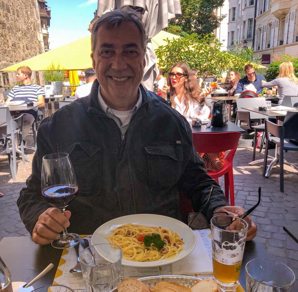 Homem sentado com taça de vinho na mão em restaurante em Genebra