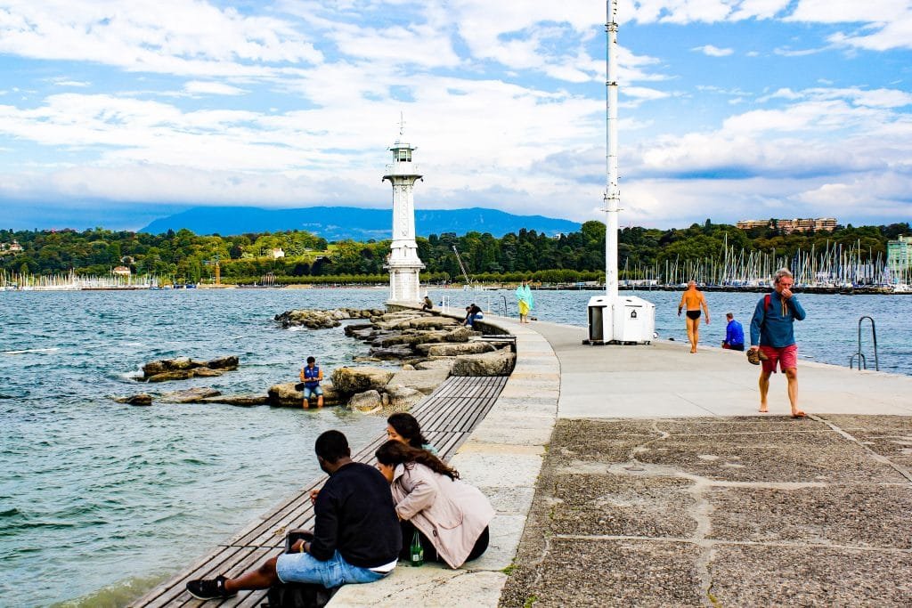 Píer com pessoas sentadas e caminhando na beira do lago Genebra