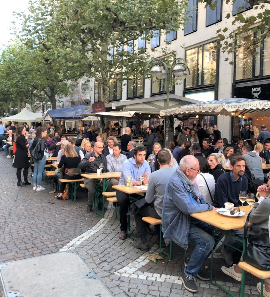 rua cheia de gente em pé e sentada em frankfurt 