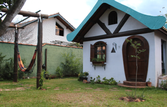 Casa de telhado azul e porta de madeira com rede na varanda 