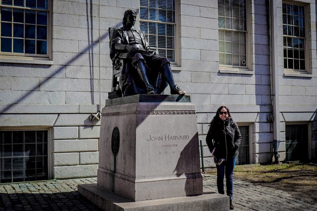 Mulher ao lado de estátua de John Harvard em Cambridge 