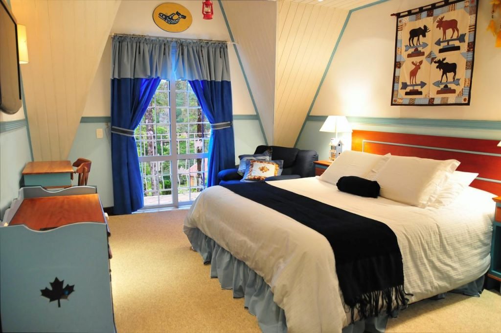 Quarto com cama de casal, poltrona e cortinas azuis