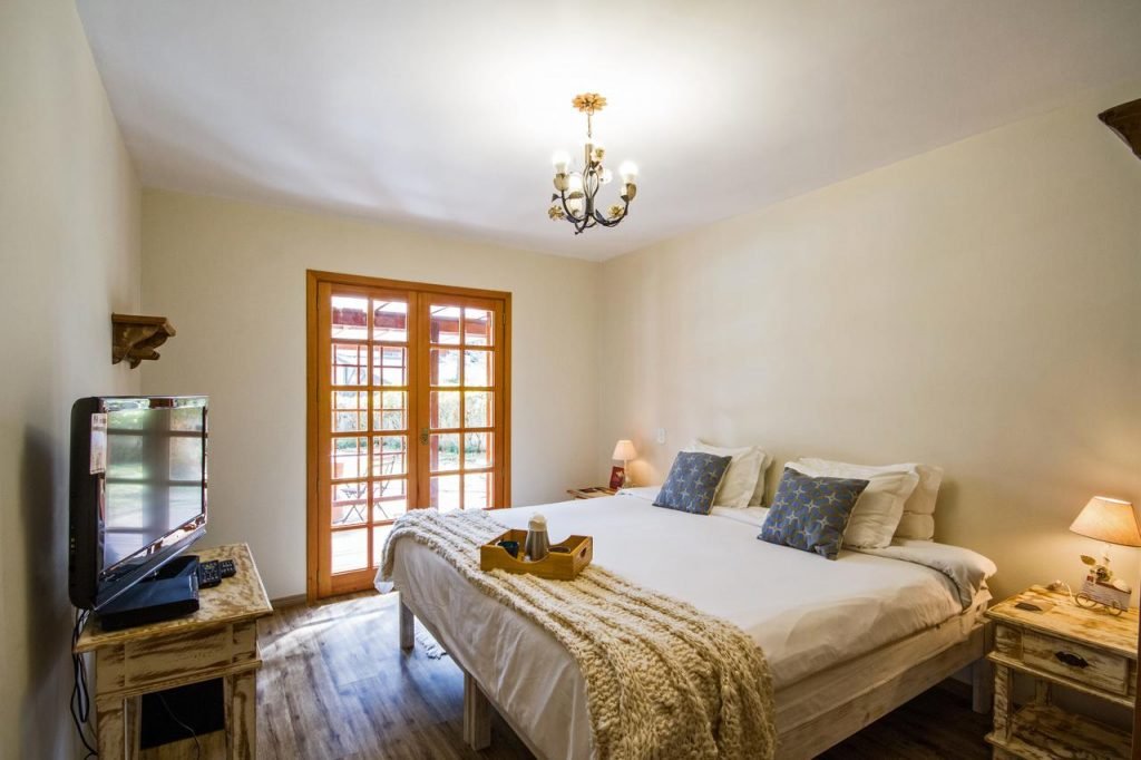 Quarto com cama de casal, cabeceiras e televisão em Campos do Jordão 