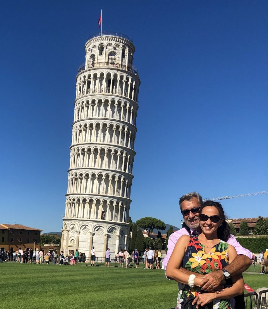Casal abraçado em frente a Torre de Pisa 